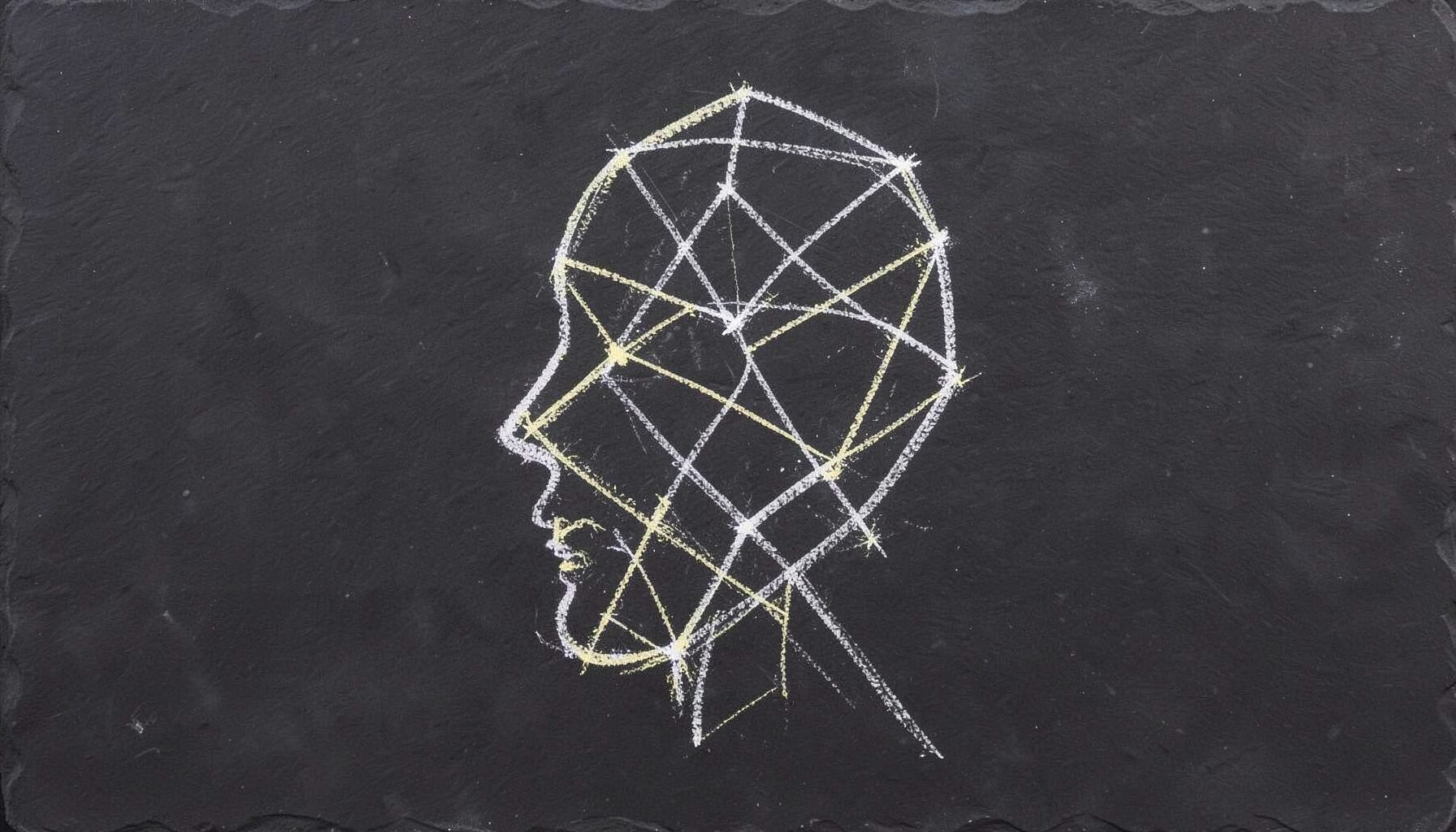 A chalk drawing on a dark slate board showing a stylized human profile composed of interconnected geometric nodes and flowing lines, in white and pale-yellow chalk